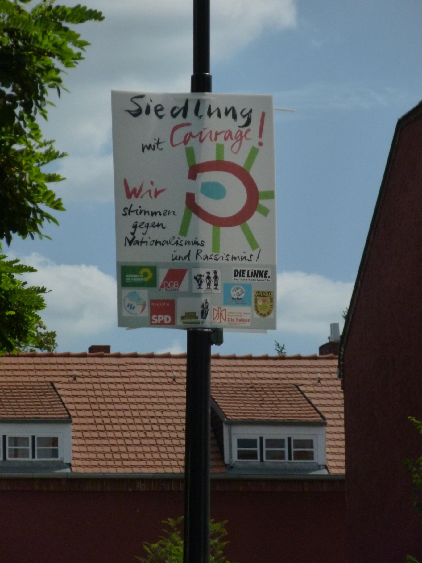 Foto eines hängenden Plakats mit der Aufschrift: Siedlung mit Courage! Wir stimmen gegen Nationalismus und Rassismus!